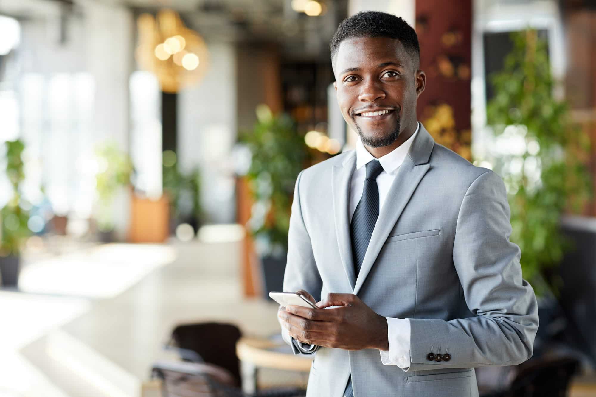 Cheerful young African-American businessman with smartphone