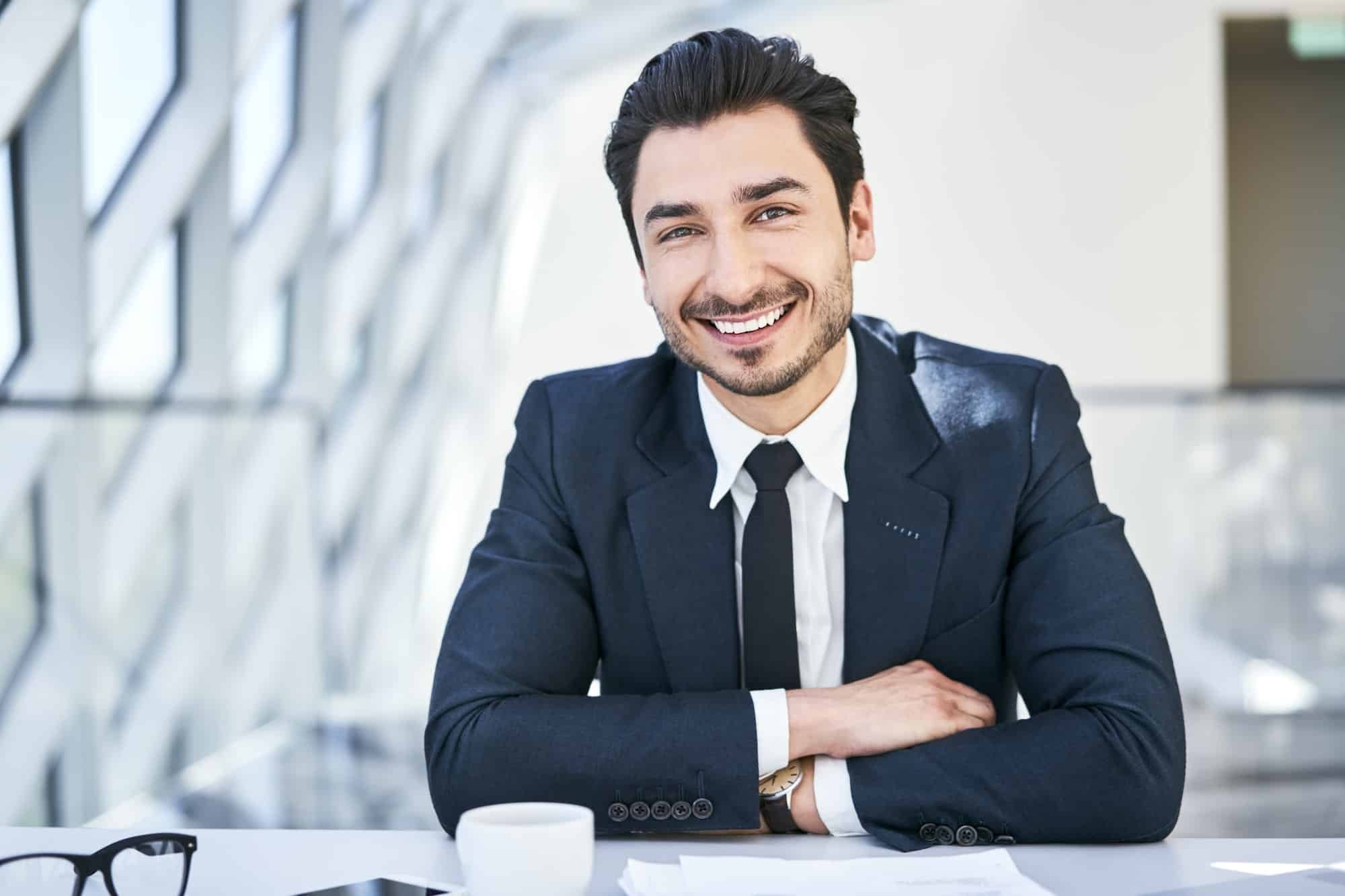 Portrait of smiling businessman at desk in modern office