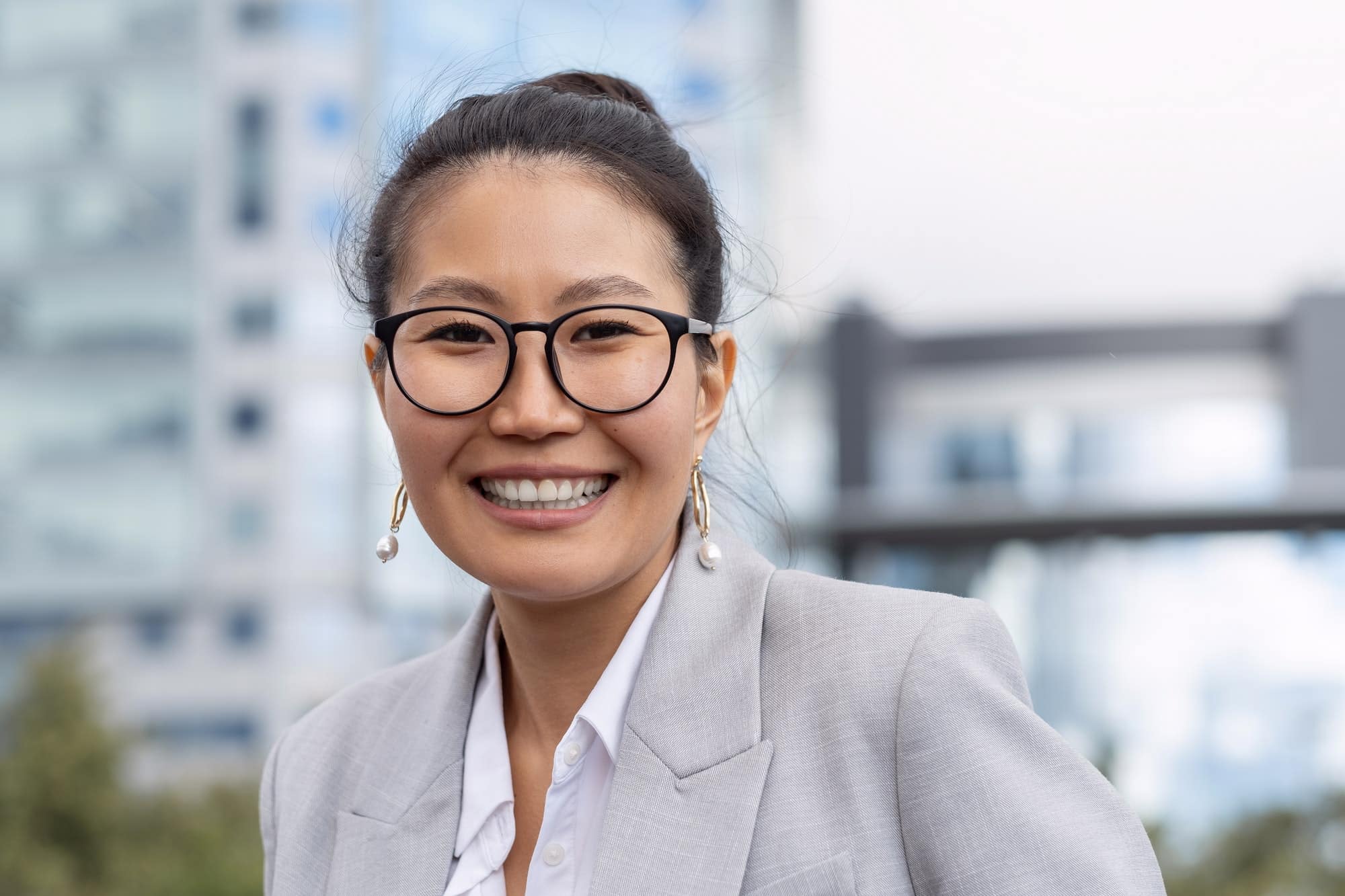Young cheerful businesswoman in eyeglasses and grey suit
